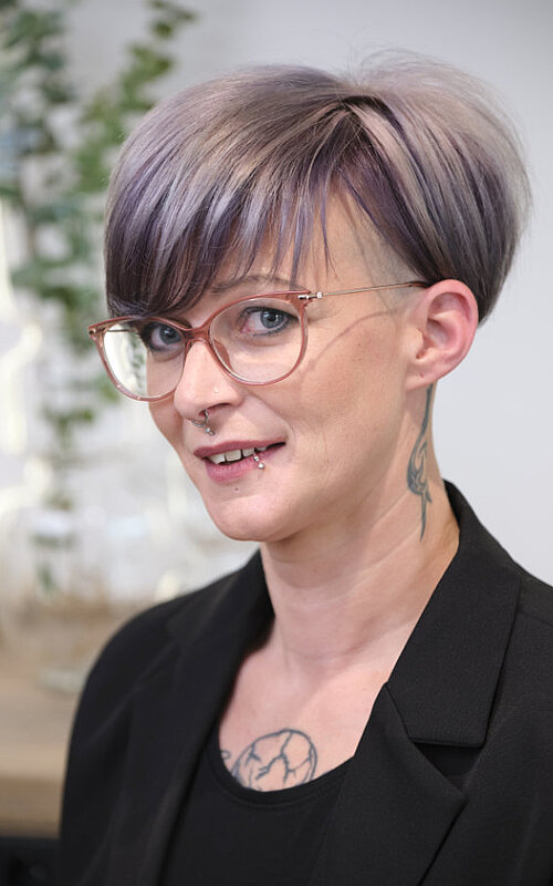 Friseurin C. Kohn Porträt von C. Kohn, eine Friseurin mit kurzem grauen Haar, in einem modernen Friseursalon.