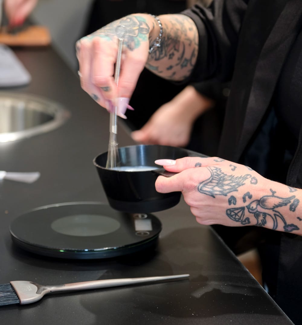 Friseursalon von HEIMATFRISEURE mit einem Friseur bei der Arbeit beim anmischen von Farben. Fokus auf die Hände.
